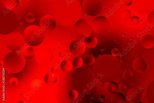 bright oily drops in water with colorful background, close-up 