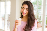 Beautiful young girl drinking a cup of coffee at home and smiling