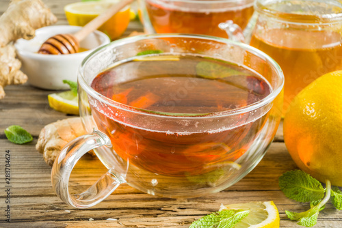 Autumn tea with mint and lemon with ingredients - fresh mint leaves, sliced lemon and honey, rustic wooden background copy space