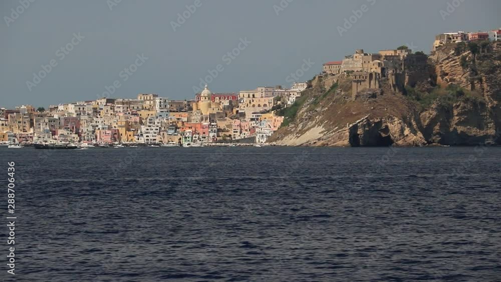 The island of Procida seen from the sea. The village of Corricella with colorful houses and the ancient castle on the mountain. The island of Procida seen from the sea. The village of Corricella with colorful houses and the ancient castle on the mountain.