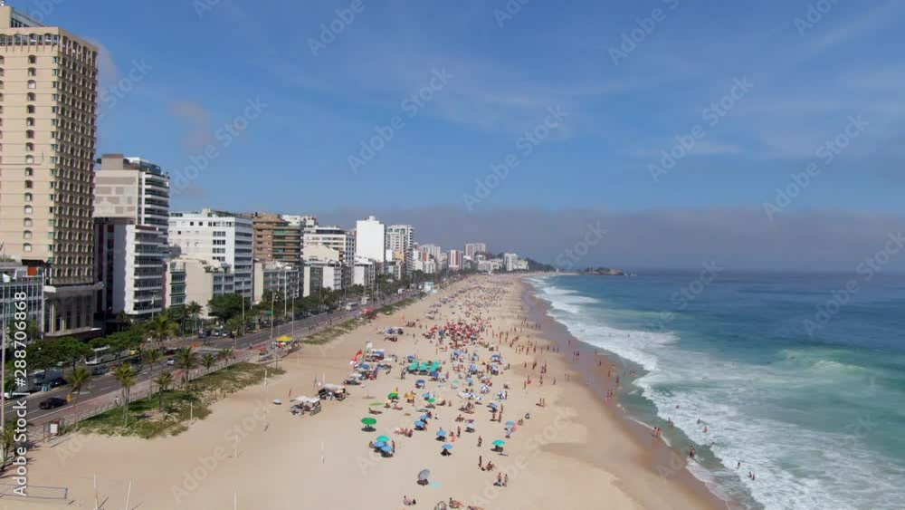 Rio de Janeiro, Brazil, flyover shot of famous Ipanema Beach showing colourful sun umbrellas and waves breaking on the shore on a sunny day. Rio de Janeiro, Brazil, flyover shot of famous Ipanema Beach showing colourful sun umbrellas and waves breaking on the shore on a sunny day.