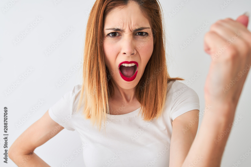 Beautiful redhead woman wearing casual t-shirt standing over isolated white background annoyed and frustrated shouting with anger, crazy and yelling with raised hand, anger concept Beautiful redhead woman wearing casual t-shirt standing over isolated white background annoyed and frustrated shouting with anger, crazy and yelling with raised hand, anger concept