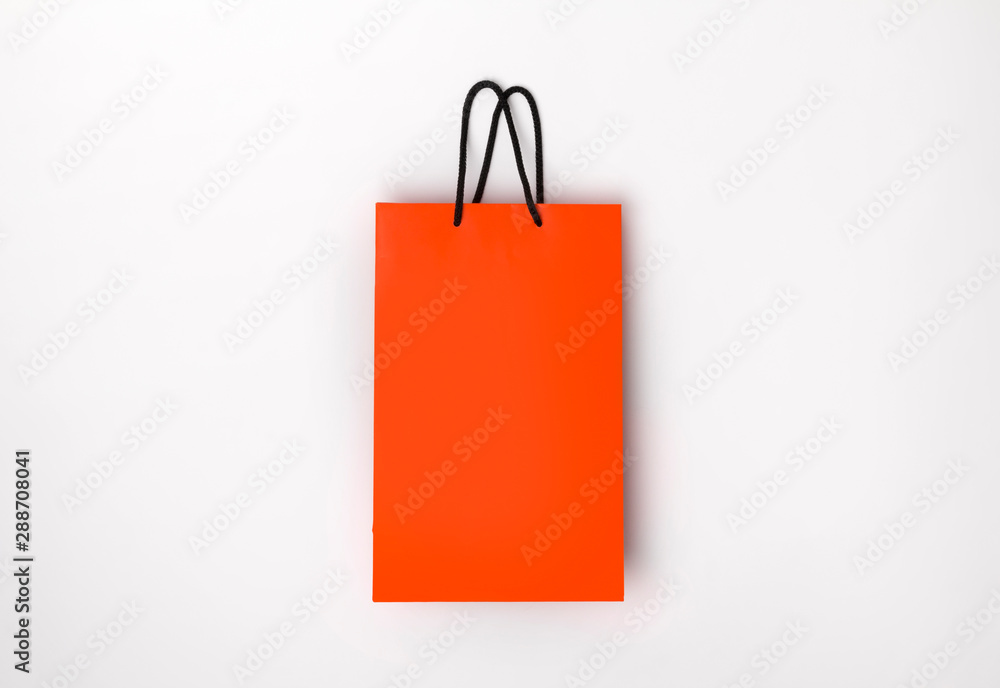 Orange paper shopping bag with black handles on the white background Orange paper shopping bag with black handles on the white background