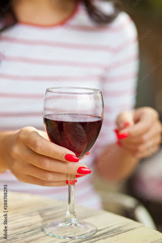 Woman puts glass of red wine in outdoor cafe