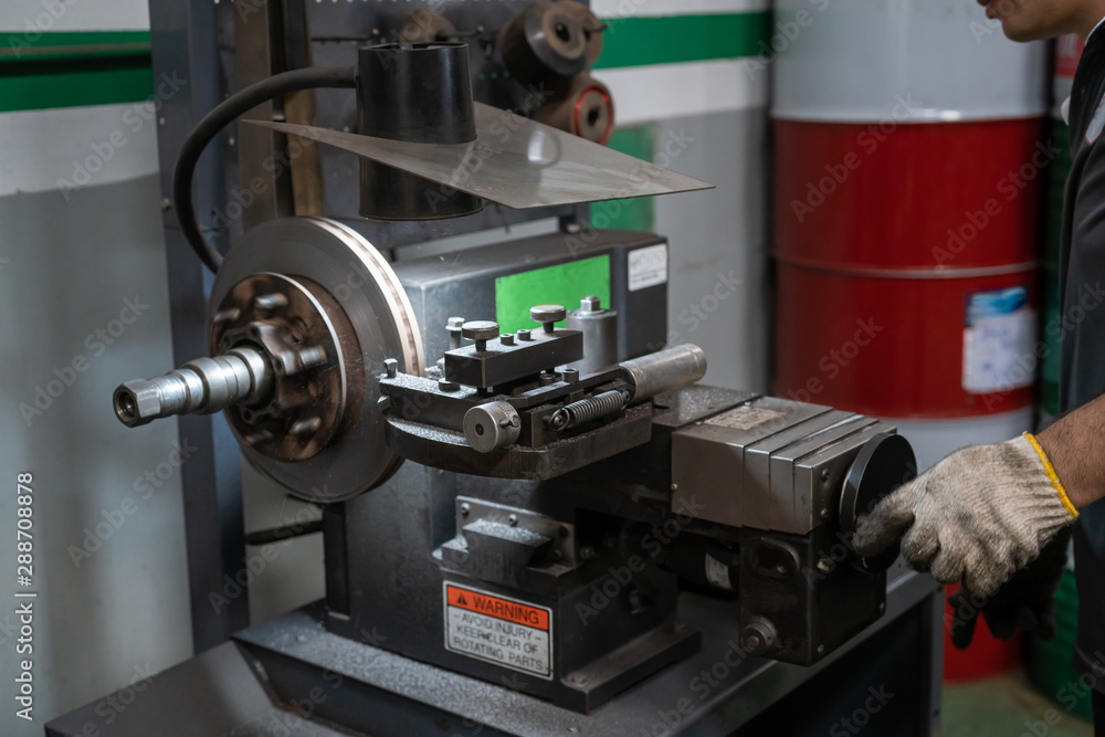 Mechanic man repairing brake use lathe tool polishing disc brakes of cars working automatic. - rebuild disc brake surface.