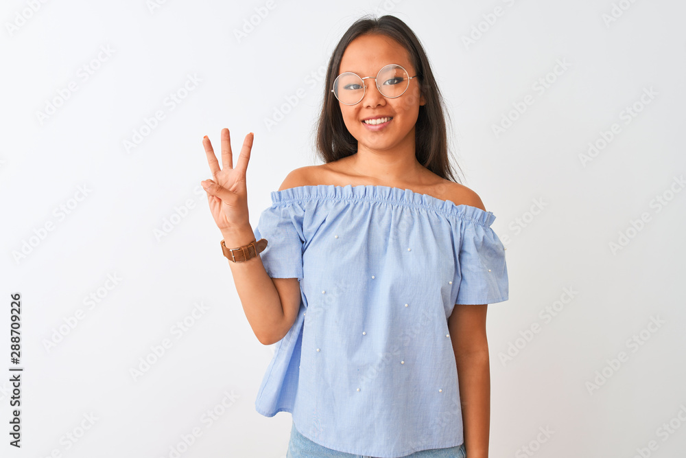 Young chinese woman wearing blue t-shirt and glasses over isolated white background showing and pointing up with fingers number three while smiling confident and happy. Young chinese woman wearing blue t-shirt and glasses over isolated white background showing and pointing up with fingers number three while smiling confident and happy.
