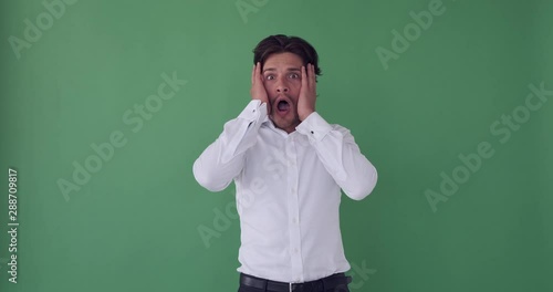 Businessman looking away with shocked expression over green background