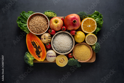 a pot of fresh seasonal fruits and vegetables and grains of legumes on a black background