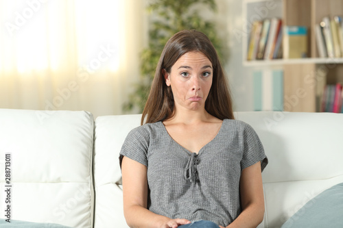 Bilde på lerret Perplexed woman looking at camera sitting at home