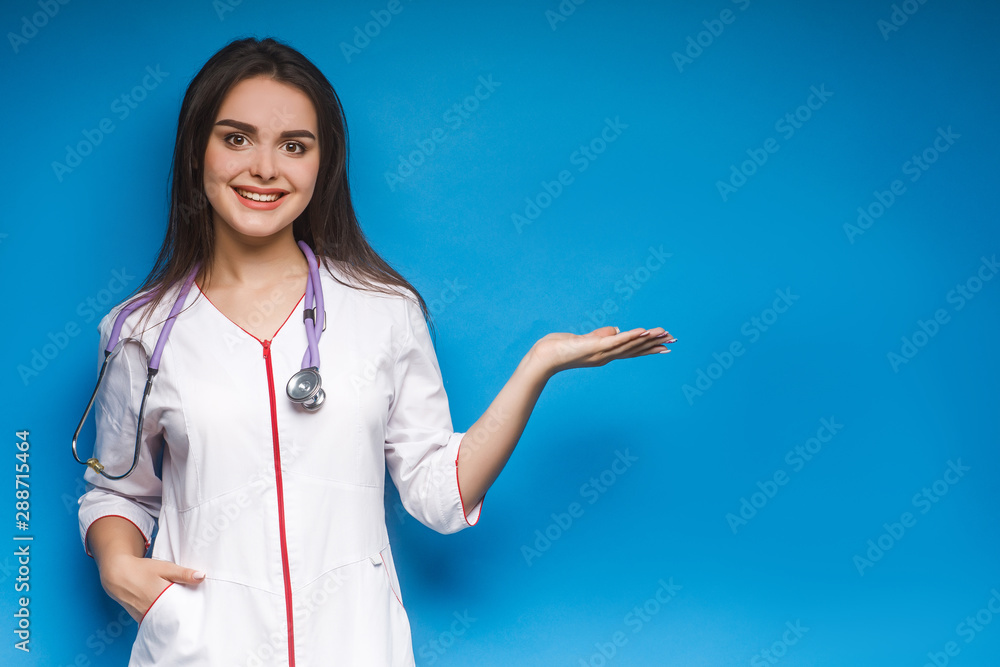Portrait of young female doctor showing something or copyspase for product or sign text, over blue background. Can used for instagram. Portrait of young female doctor showing something or copyspase for product or sign text, over blue background. Can used for instagram.