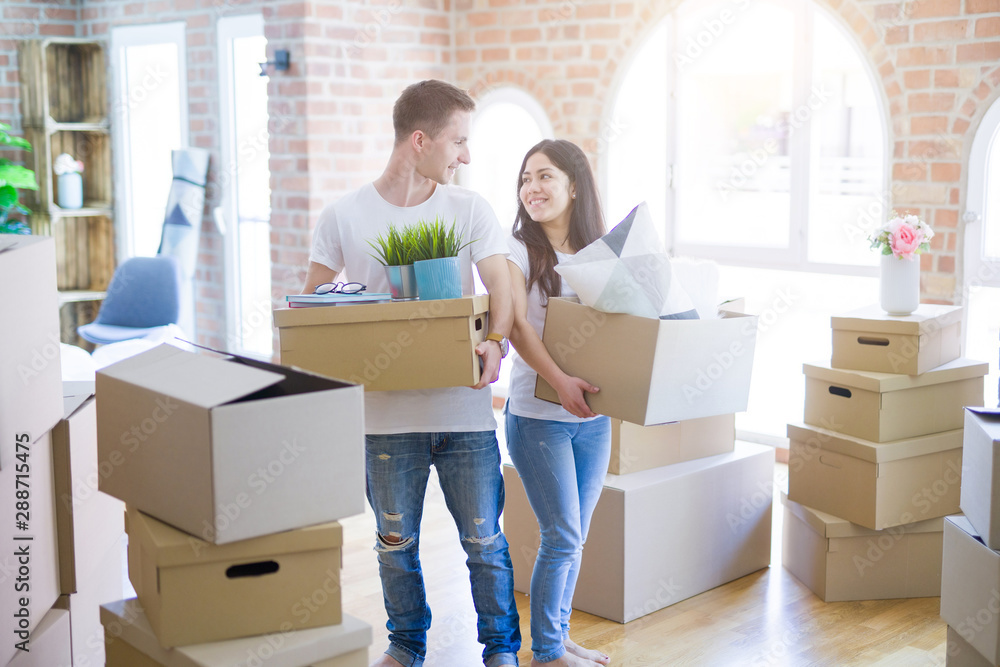 Young beautiful couple moving cardboard boxes at new home Young beautiful couple moving cardboard boxes at new home