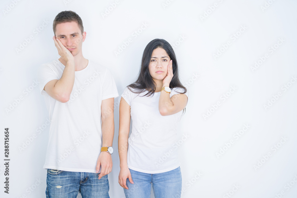 Young beautiful couple wearing casual t-shirt standing over isolated white background thinking looking tired and bored with depression problems with crossed arms. Young beautiful couple wearing casual t-shirt standing over isolated white background thinking looking tired and bored with depression problems with crossed arms.