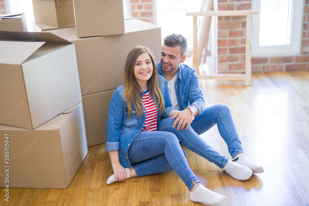 Young beautiful couple in love moving to new home, sitting on the floor very happy and cheerful for new apartment around cardboard boxes Young beautiful couple in love moving to new home, sitting on the floor very happy and cheerful for new apartment around cardboard boxes