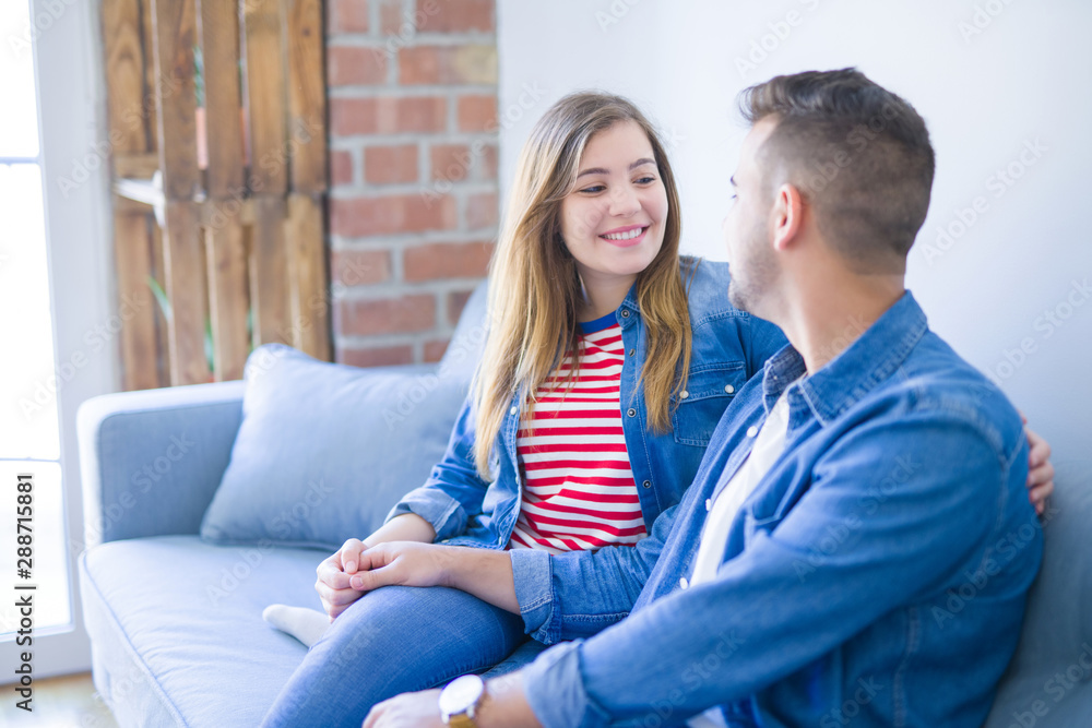 Young beautiful couple sitting hugging in love on the sofa at home Young beautiful couple sitting hugging in love on the sofa at home