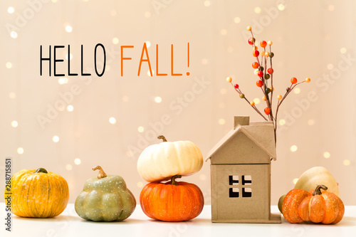 Hello fall message with collection of autumn pumpkins with a toy house