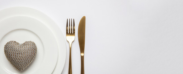 Table setting, wedding reception. Gold cutlery on white set of dishes, white background