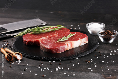 Steak raw. Barbecue Rib Eye Steak or rump steak on dark rustic table photo