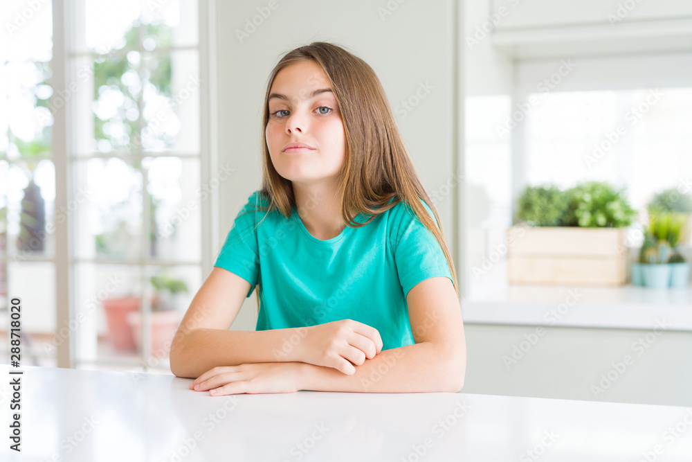 Beautiful young girl kid wearing green t-shirt with serious expression on face. Simple and natural looking at the camera. Beautiful young girl kid wearing green t-shirt with serious expression on face. Simple and natural looking at the camera.