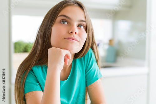 Beautiful young girl kid wearing green t-shirt with hand on chin thinking about question, pensive expression. Smiling with thoughtful face. Doubt concept. Free Download Beautiful young girl kid wearing green t-shirt with hand on chin thinking about question, pensive expression. Smiling with thoughtful face. Doubt concept. - GFXLoad