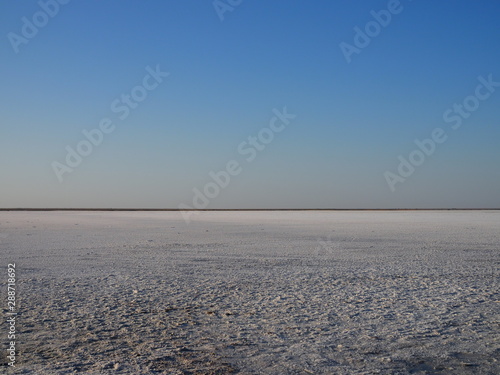 white surface of the lake covered with salt at sunrise