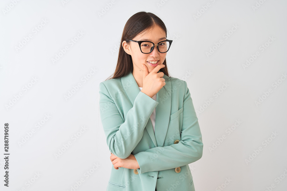 Chinese businesswoman wearing elegant jacket and glasses over isolated white background looking confident at the camera smiling with crossed arms and hand raised on chin. Thinking positive.