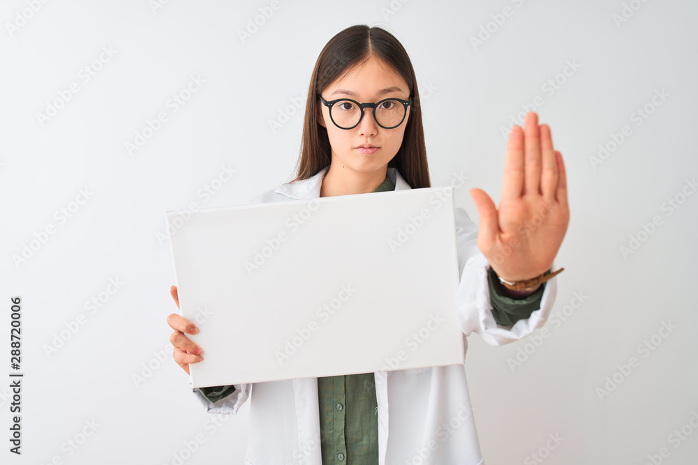 Naklejka premium Young chinese dooctor woman wearing glasses holding banner over isolated white background with open hand doing stop sign with serious and confident expression, defense gesture