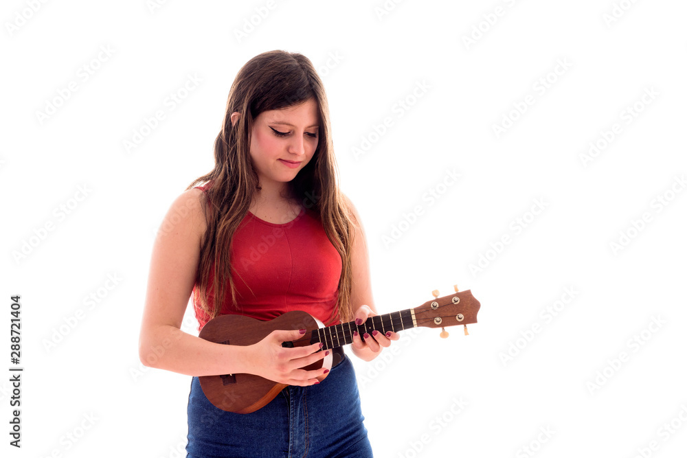 Teenage girl playing a ukelele, young artist with her musical instrument isolated Teenage girl playing a ukelele, young artist with her musical instrument isolated