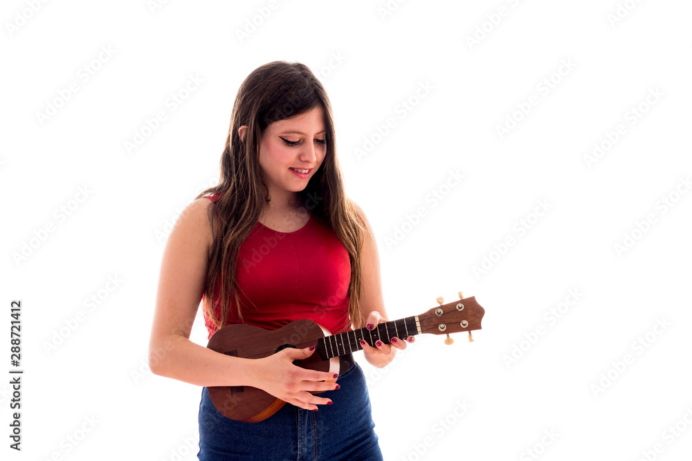 Teenage girl playing a ukelele, young artist with her musical instrument isolated Teenage girl playing a ukelele, young artist with her musical instrument isolated