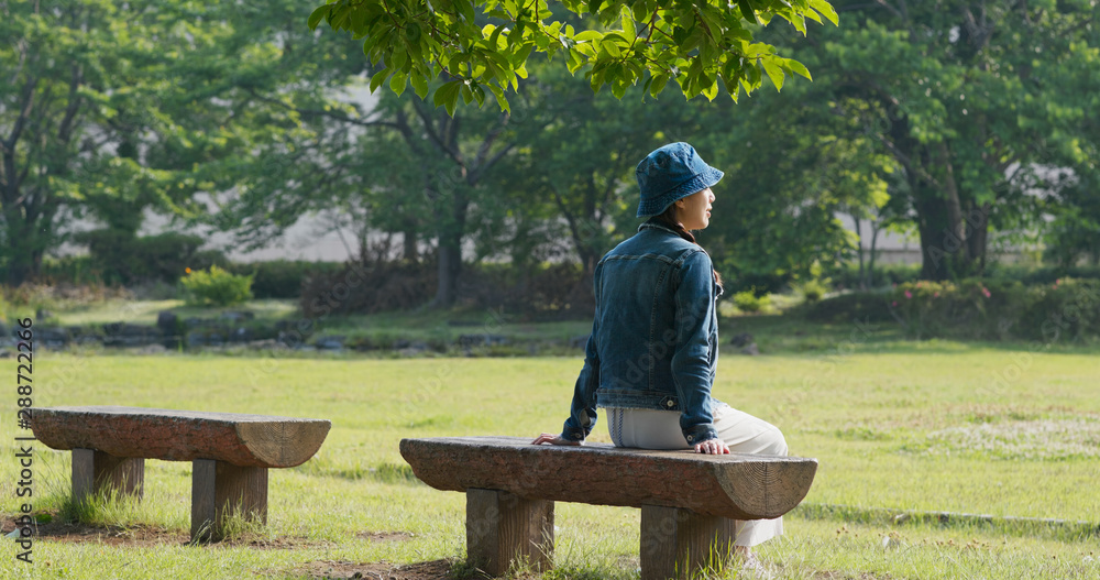 Fototapeta premium Woman sits on the wooden bench
