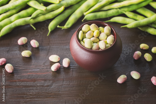 beans in a ceramic pot on the kitchen table. background with beans. the pods and beans closeup.