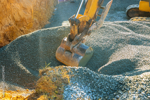 Excavatorsmoving gravel in the construction works of a foundation of the house. photo