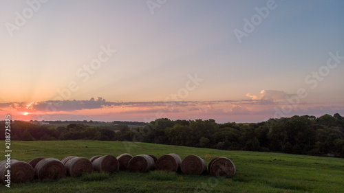 Sunrise over round hay bales in a field in Nebraska