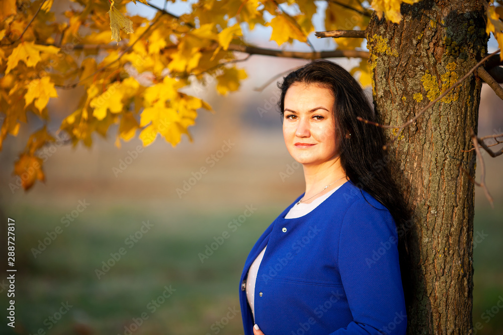 Golden autumn. Beautiful brunette caucasian woman in a blue cardigan in the city park. Yellow leaves. Golden autumn. Beautiful brunette caucasian woman in a blue cardigan in the city park. Yellow leaves.