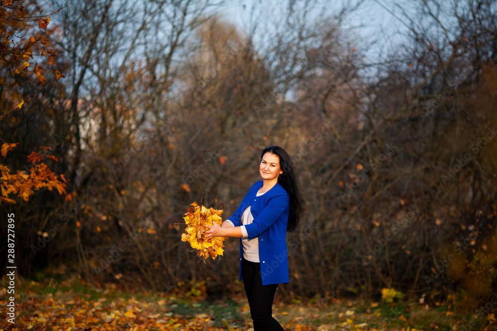Golden autumn. Beautiful brunette caucasian woman in a blue cardigan in the city park. Yellow leaves. Golden autumn. Beautiful brunette caucasian woman in a blue cardigan in the city park. Yellow leaves.