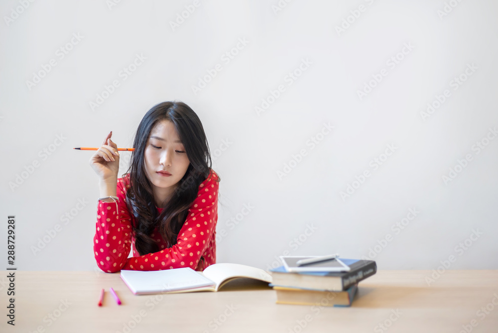 Young beautiful Asian woman reading a book while doing her homework in the modern co working space Young beautiful Asian woman reading a book while doing her homework in the modern co working space