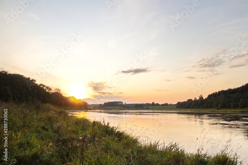 Sunset by the river in the summer countryside