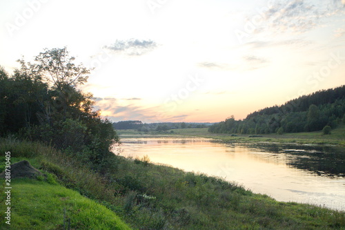 Sunset by the river in the summer countryside