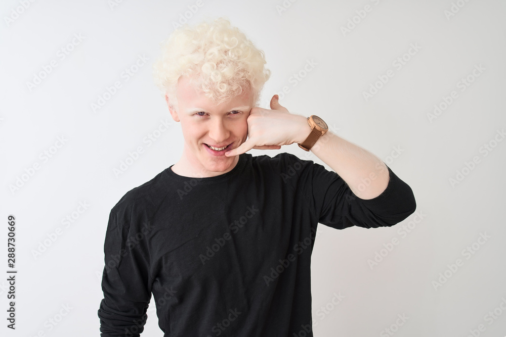 Young albino blond man wearing black t-shirt standing over isolated white background smiling doing phone gesture with hand and fingers like talking on the telephone. Communicating concepts. Young albino blond man wearing black t-shirt standing over isolated white background smiling doing phone gesture with hand and fingers like talking on the telephone. Communicating concepts.