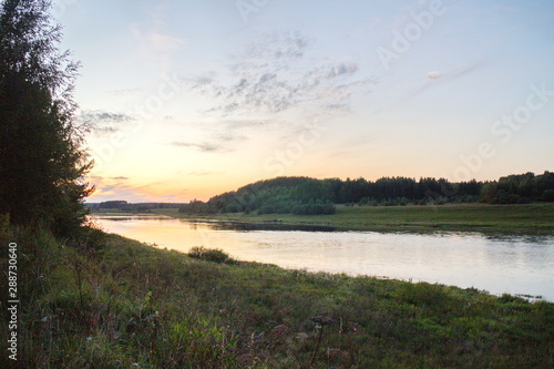 Sunset by the river in the summer countryside