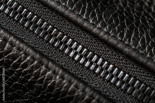 Close-up of the lock on a bag made of genuine black leather, on a dark background