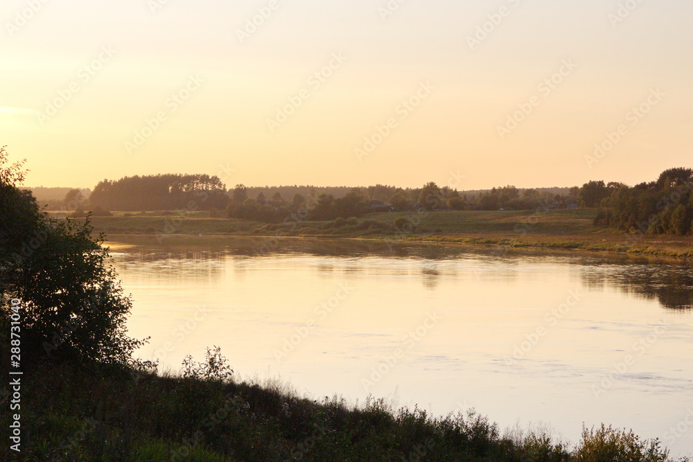 Sunset by the river in the summer countryside