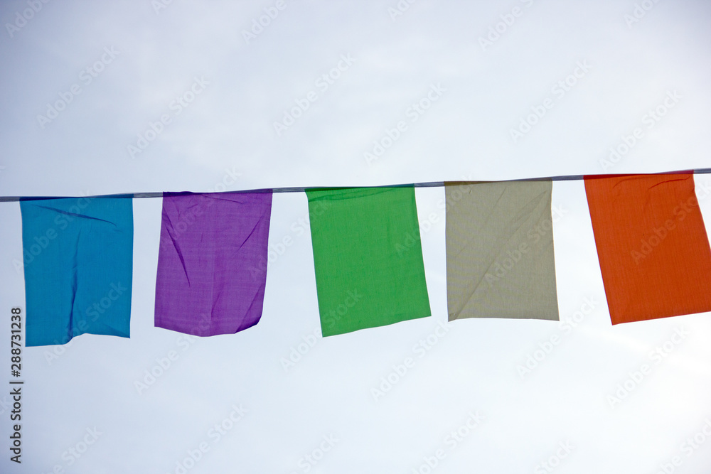 Garland of multi-colored flags on a city street festival. Street decoration for the holiday. Multi-colored pennant, flags on the rope, festive decoration. Flags garland for fun festa party event.