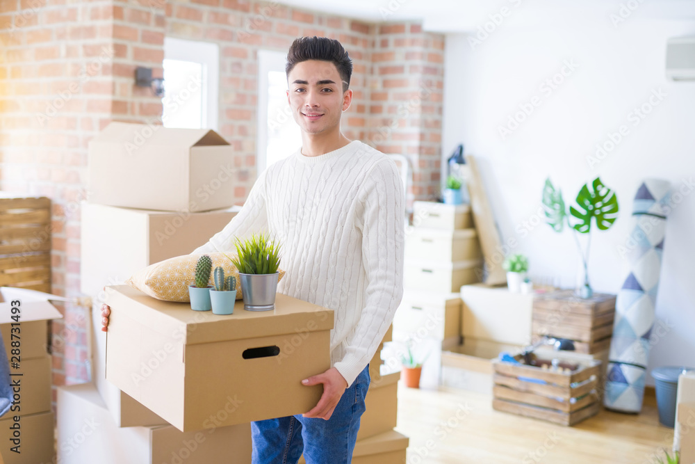 Young man smiling holdig cardboard box, happy moving to a new house Young man smiling holdig cardboard box, happy moving to a new house