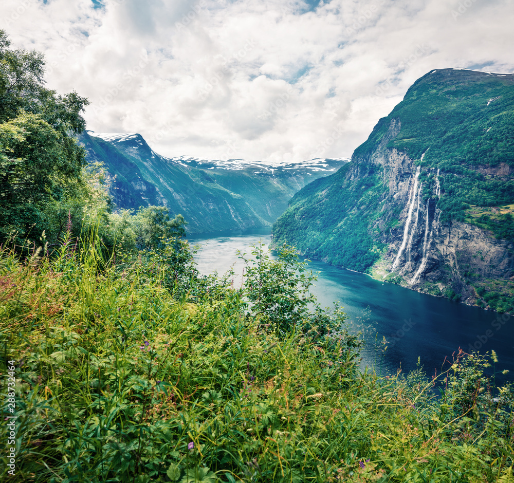 Amazing summer scene of Sunnylvsfjorden fjord, Geiranger village location, western Norway. Majestic view of famous Seven Sisters waterfalls. Beauty of nature concept background. 