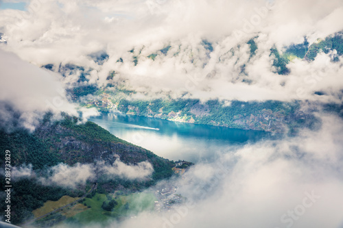 Foggy summer view of Sognefjorden fjord. Picturesque morning scene with Aurlandsvangen village  Norway. Traveling concept background. Artistic style post processed photo.