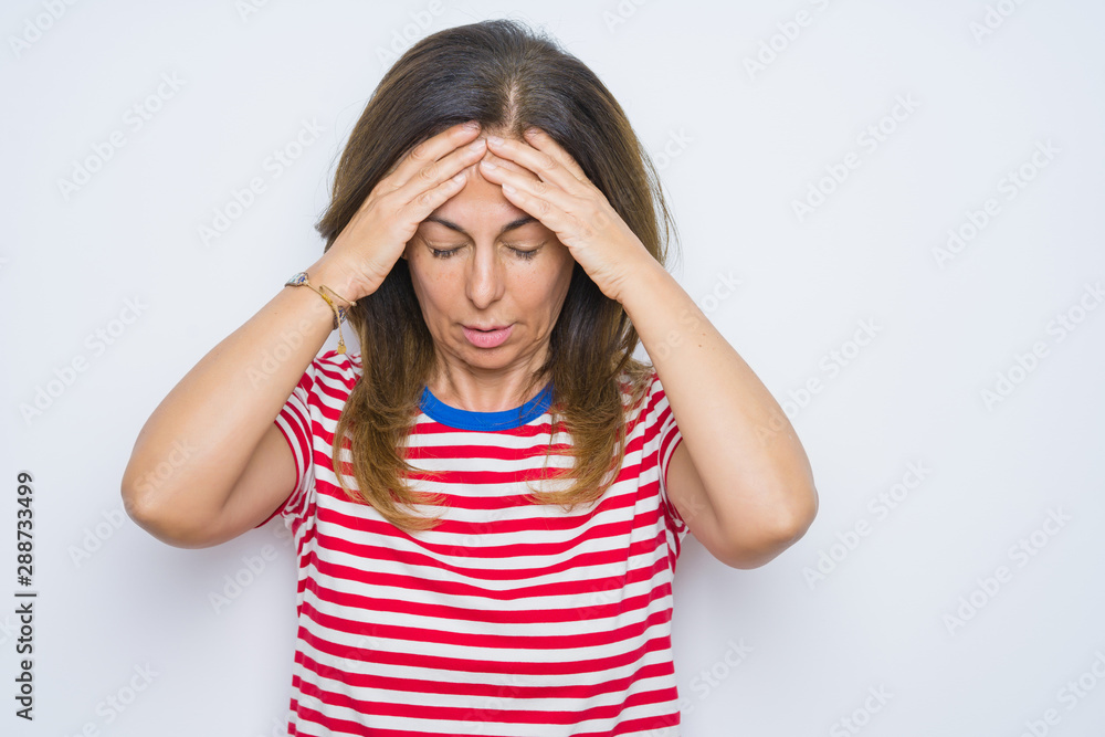 Middle age senior woman standing over white isolated background suffering from headache desperate and stressed because pain and migraine. Hands on head. Middle age senior woman standing over white isolated background suffering from headache desperate and stressed because pain and migraine. Hands on head.
