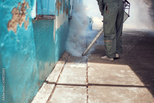 Man work fogging to eliminate mosquito for preventing spread dengue fever in the community