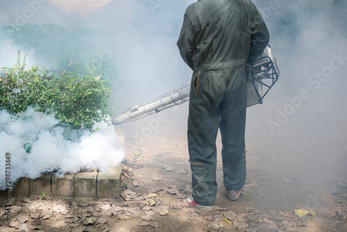 Man work fogging to eliminate mosquito for preventing spread dengue fever in the community