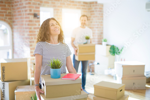 Middle age senior couple moving to a new house, smiling woman holding cardboard boxes and packaging © Krakenimages.com