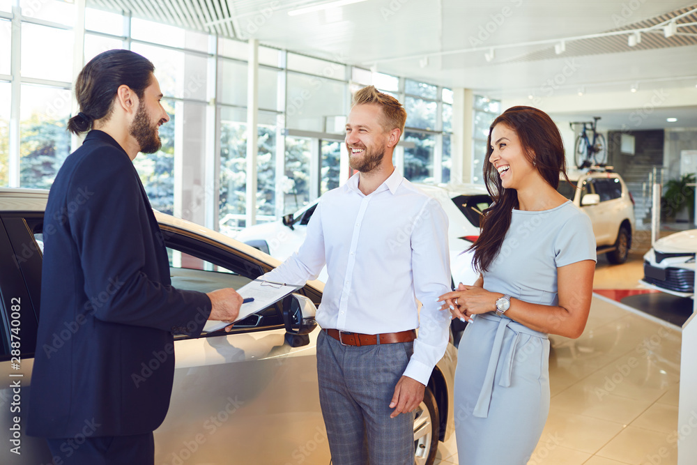 A car salesman and a buyer shake hands. A couple buys a car A car salesman and a buyer shake hands. A couple buys a car